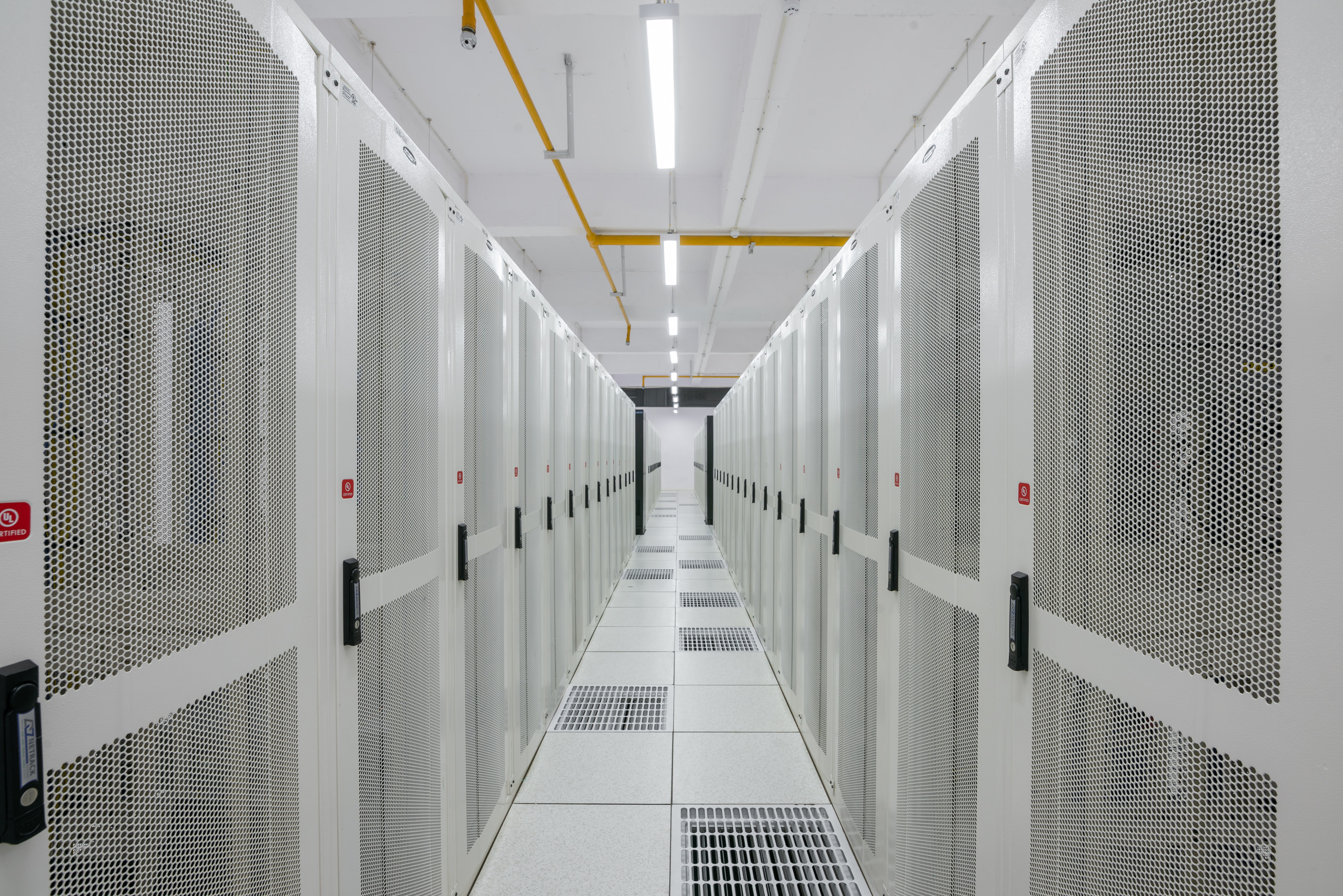 Illustrative photo: a white server-rack aisle inside a data centre (Pi Data Centers, Amaravati, India), not the Riyadh project site